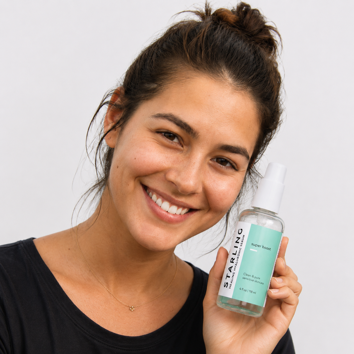 Woman with sensitive skin smiling while holding Starling Super Boost Healing Hyaluronic Serum